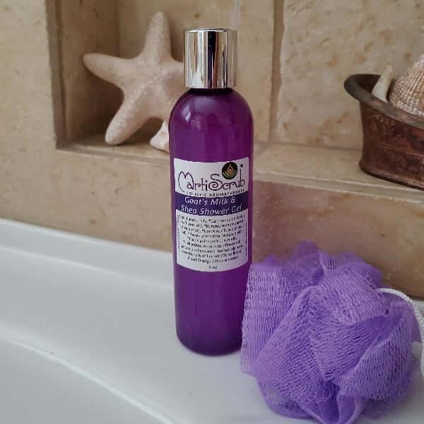 Goat's Milk and Shea Shower Gel in purple bottle with a loofah, perfect for soft and nourished skin care.