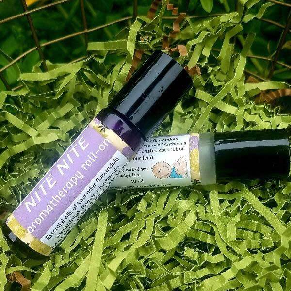 NITE NITE BABY Essential Oil Roll-On bottles on green shredded paper, featuring lavender and chamomile oils for calming infants.