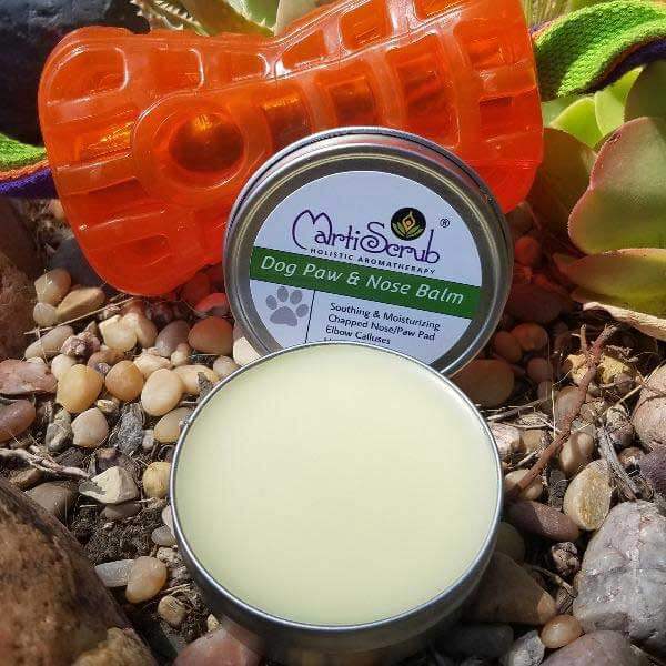Organic Dog Paw and Nose Balm in a tin, surrounded by pebbles and a bright toy, ideal for soothing dry skin.