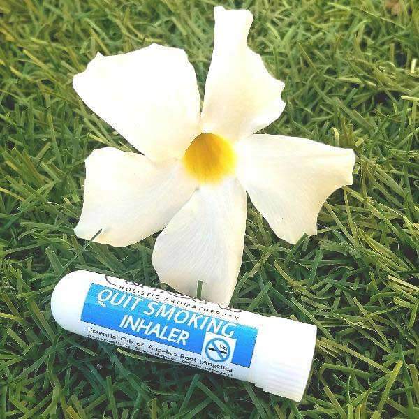 Aromatherapy quit smoking inhaler with essential oils beside a white flower on grass.
