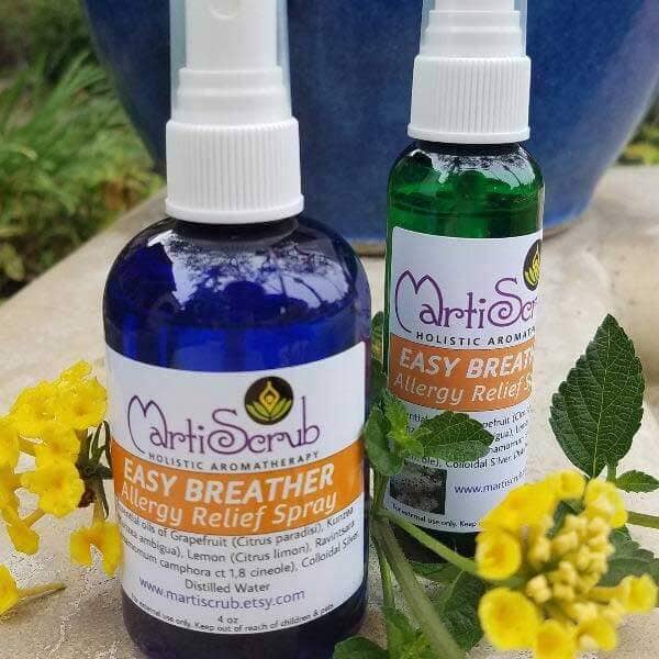 Two bottles of Easy Breather allergy relief spray with essential oils, surrounded by yellow flowers and green leaves.