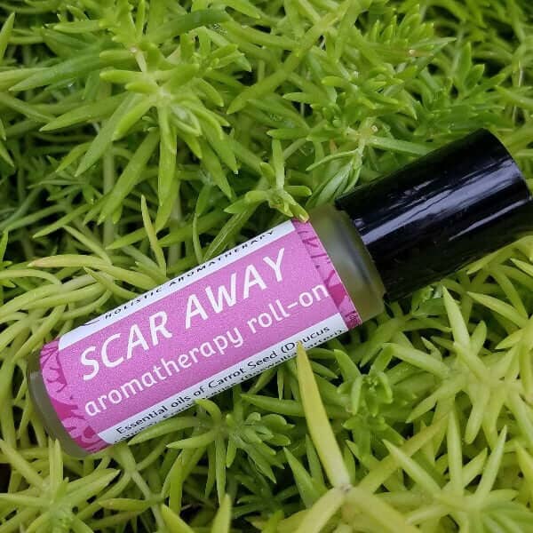 SCAR AWAY aromatherapy roll-on promoting skin healing with organic ingredients against a backdrop of greenery.
