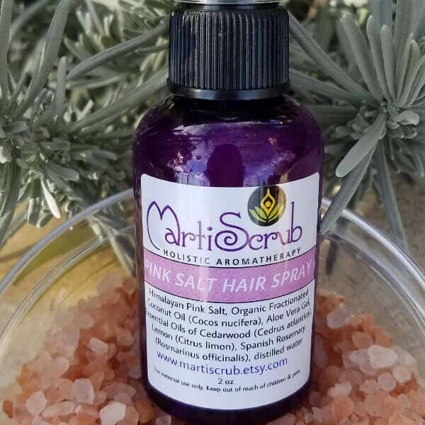 Pink Salt Hair Spray bottle featuring essential oils for volume, texture, and frizz control, surrounded by Himalayan pink salt.